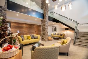 a living room with yellow furniture and a staircase at Walliserhof Grand-Hotel & Spa Relais & Châteaux in Saas-Fee