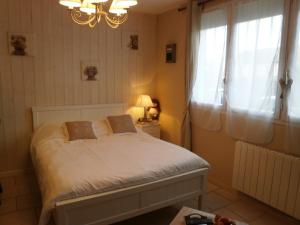 a bedroom with a bed and a chandelier and a window at Au 14 Honfleur parking privé in Honfleur