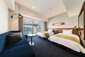 川崎市にあるホテルメトロポリタン 川崎のベッド2台とソファが備わるホテルルームです。