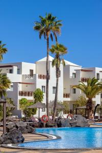 a resort with a swimming pool and palm trees at Vitalclass Lanzarote Resort in Costa Teguise