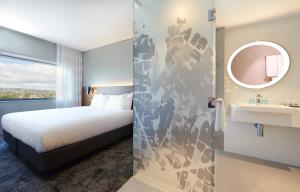 a room with a bed, a mirror, and a painting on the wall at Holiday Inn Express Newcastle, an IHG Hotel in Newcastle