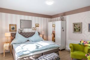 a bedroom with a bed and a green chair at Sonnenhof Plauen in Plauen