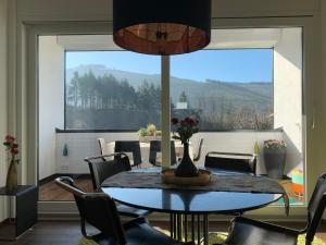 a dining room with a table and chairs and a large window at Luxus-Ferienwohnung Saalhausen in Saalhausen