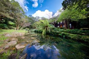 einen Teich inmitten eines Gartens mit einem Haus in der Unterkunft Yanmin Hot Spring Resort in Taipeh