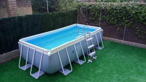 a small swimming pool on a green lawn at Los Alisos Casa Rural in Guadalix de la Sierra