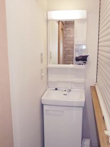 a white bathroom with a sink and a mirror at Hotel Lucky in Osaka