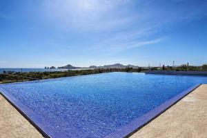 a large blue swimming pool with a view of the ocean at Luxe Cabo Condo w/ Ocean Views + Amenities! in Cabo San Lucas