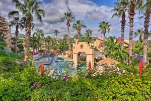 a resort pool with palm trees in the background at Resort-Style Cabo Getaway with Pools & Ocean Views in Cabo San Lucas