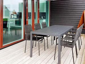 a table and chairs on a deck with a kitchen at 6 person holiday home in R m in Sønderby