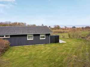 ein schwarzes Haus auf einem Feld mit einem Rasenplatz in der Unterkunft 6 person holiday home in Allinge in Allinge
