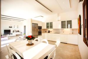 a white kitchen with a table and white chairs at Casa Lavanda in Cala Saona