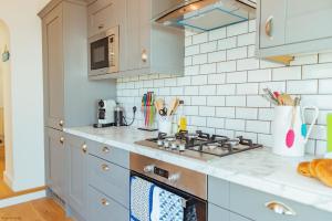 eine Küche mit Herd und Arbeitsplatte in der Unterkunft Driftwood Cottage by Bloom Stays in Folkestone + 26 Fotos