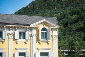 a yellow house with a mountain in the background at Hotel Stiegl Scala in Bolzano