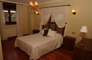 a bedroom with a bed with white sheets and a chandelier at CASA RURAL LAR DE VILARINO in Poio