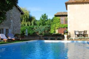 una piscina en un patio con 2 sillas y una casa en Manoir du Bois Mignon Luxury Home - Dordogne en Le Fleix
