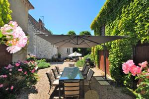 um pátio com uma mesa, cadeiras e um guarda-sol em Manoir du Bois Mignon Luxury Home - Dordogne em Le Fleix