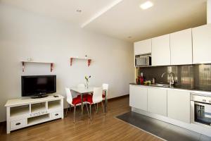 une cuisine avec des placards blancs et une table avec des chaises dans l'établissement PobleNou Loft Nº2 By MyRentalHost, à Barcelone