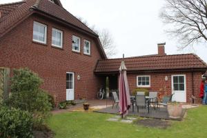 a house with a patio and an umbrella in the yard at Ferienwohnung Hooge Loogen, 35212 in Holtland