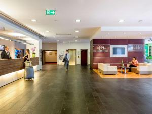 a man walking through a lobby of a building at Mercure Hotel München Süd Messe in Munich