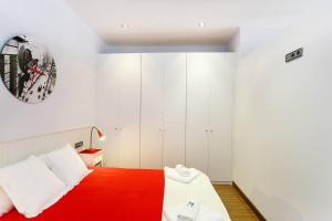 a bedroom with a red and white bed with a clock on the wall at Poblenou Loft Nº1 By MyRentalHost in Barcelona