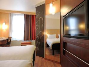 a hotel room with a bed and a flat screen tv at ibis Montpellier Centre Polygone in Montpellier