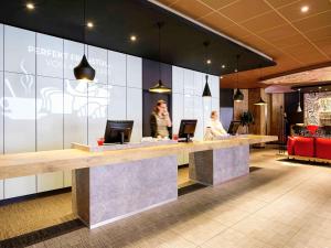 a lobby with a counter with two people sitting at it at ibis Hotel Hamburg Alster Centrum in Hamburg