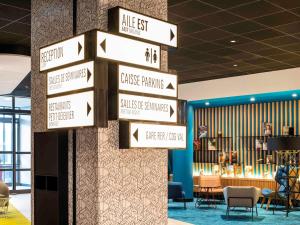 a group of signs on a wall in a lobby at ibis Paris CDG Airport in Roissy-en-France