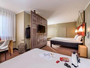 a hotel room with a bed and a room with a penguin at ibis Frankfurt Centrum in Frankfurt/Main