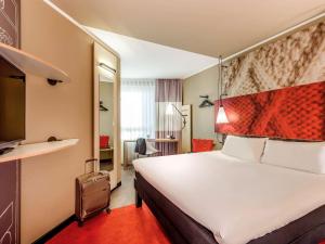 a hotel room with a large bed and a red carpet at ibis Hotel München City in Munich