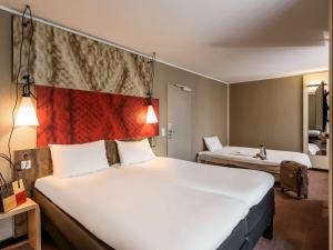 
a hotel room with a large bed and a large window at ibis Hotel München City in Munich
