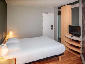 a bedroom with a white bed and a television at Ibis Brussels City Centre in Brussels