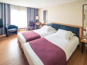a hotel room with two beds and a television at Mercure Montpellier Centre Antigone in Montpellier