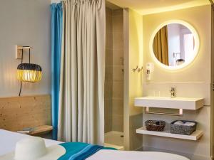 a bathroom with a bed and a sink and a mirror at ibis Thalassa Hyeres Plage in Hyères