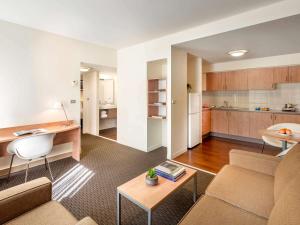 a living room with a couch and a table and a kitchen at ibis Melbourne Hotel and Apartments in Melbourne