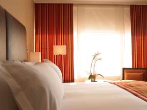 - une chambre avec des draps blancs, une fenêtre et un lit dans l'établissement Pullman Madrid Airport & Feria, à Madrid