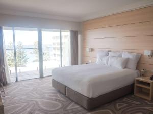 a bedroom with a large bed and a large window at Novotel Wollongong Northbeach in Wollongong
