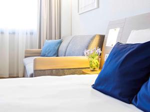 Habitación de hotel con cama y sofá en Novotel Genova City en Génova