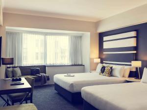 a hotel room with two beds and a couch at Mövenpick Hotel Auckland in Auckland