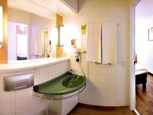 a bathroom with a green sink and a mirror at Ibis Linz City in Linz