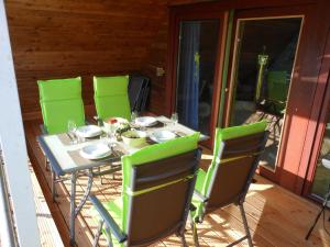 a table with green chairs on a patio at Ferienwohnung An der Eichenallee, 35200 in Hesel