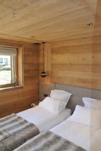 two beds in a room with wooden walls at Chalet Teleporte in Les Gets