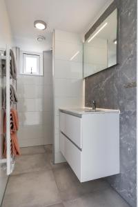 ein Badezimmer mit einem weißen Waschbecken und einem Spiegel in der Unterkunft Appartementen Parkzicht in Bergen aan Zee