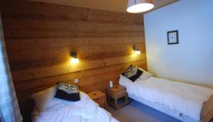 シャテルにあるMontbeliarde - Chalet avec jacuzzi - BO Immobilier- remises sur les forfaits de skis Châtel ou Portes du soleilの木製の壁の部屋にベッドが2つある