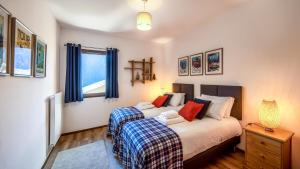 1 dormitorio con 2 camas y cortinas azules en L'O Rouge - Apt A102 - BO Immobilier- Châtel- Reduced prices on ski passes Châtel & Portes du Soleil, en Châtel