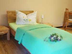 ein Bett mit einer blauen Decke, auf der ein Blumenstrauß lag in der Unterkunft Vitaleum in Krölpa + 20 Fotos