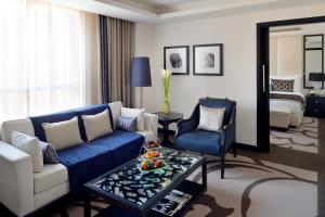 voco - Riyadh, an IHG Hotel في الرياض: غرفة معيشة مع أريكة زرقاء وطاولة
