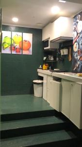 a kitchen with white cabinets and a green wall at Globetrotter Hostel in León