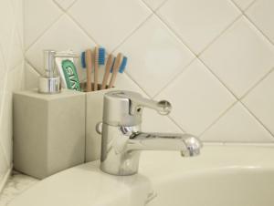 a bathroom sink with a faucet and toothbrushes at Spacebility Expo in Cagliari