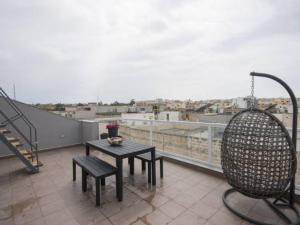 a balcony with a table and a chair on a roof at 189 Chezli Court in Birżebbuġa