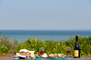 a table with food and a bottle of wine and wine glasses at La Metairie-du-Vauhariot - Lodge ou Chambre - Piscine Chauffée - Vue Mer et Mont Saint Michel - GR34 - Résidence Hôtelière in Cancale